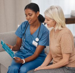 Female nurse and elder woman reading together